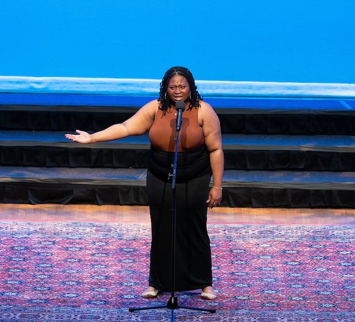 A student gestures with her hand while reciting.