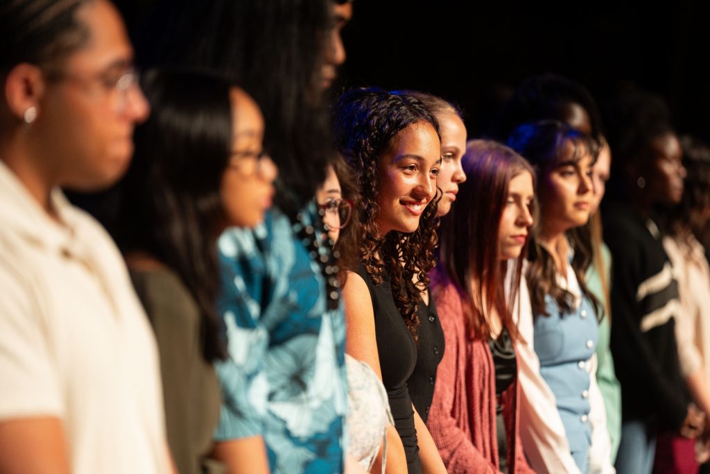A group of students stand in line on a stage.